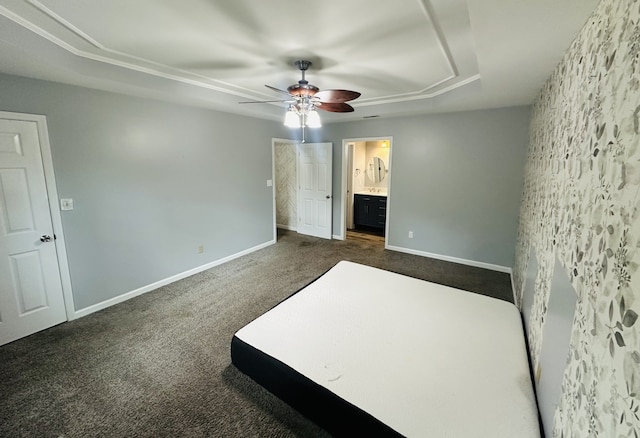 unfurnished bedroom with carpet flooring, a tray ceiling, ceiling fan, and ensuite bathroom