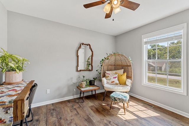 sitting room with a healthy amount of sunlight, ceiling fan, and dark hardwood / wood-style floors