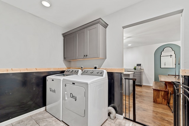 washroom featuring light wood-type flooring, cabinets, and independent washer and dryer