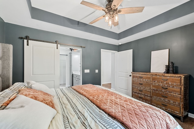 bedroom with a barn door, ceiling fan, hardwood / wood-style flooring, and ensuite bath