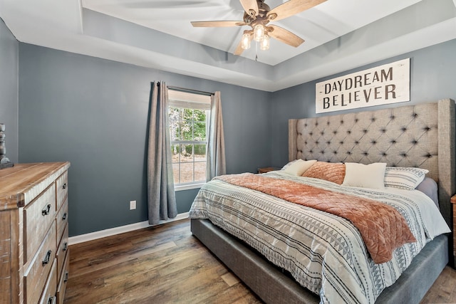 bedroom featuring dark wood-type flooring, ceiling fan, and a raised ceiling