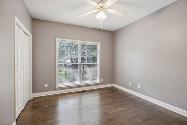 unfurnished bedroom featuring dark hardwood / wood-style flooring, ceiling fan, and a closet