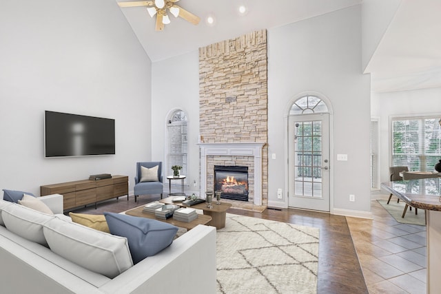 tiled living room featuring ceiling fan, a stone fireplace, and high vaulted ceiling