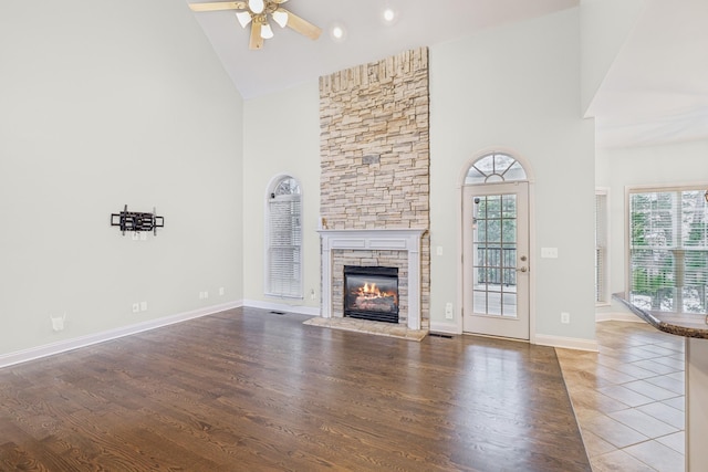 unfurnished living room with ceiling fan, a fireplace, high vaulted ceiling, and hardwood / wood-style floors