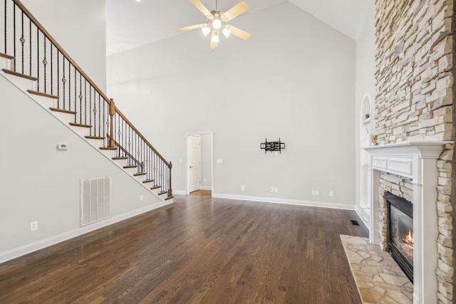 unfurnished living room with high vaulted ceiling, a stone fireplace, hardwood / wood-style flooring, and ceiling fan