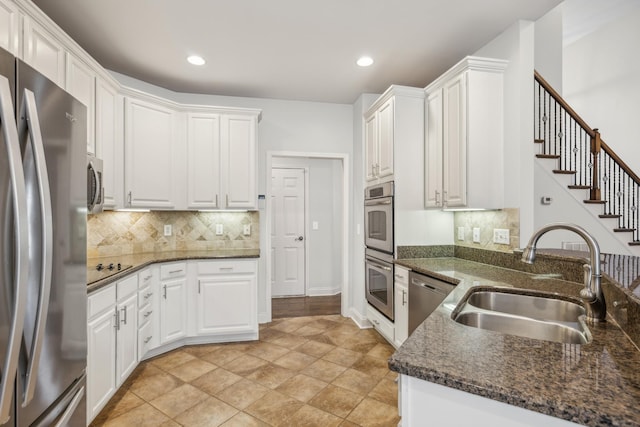 kitchen featuring backsplash, white cabinets, sink, dark stone countertops, and stainless steel appliances