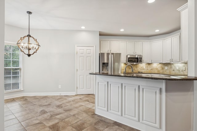 kitchen featuring white cabinets, appliances with stainless steel finishes, tasteful backsplash, decorative light fixtures, and a chandelier