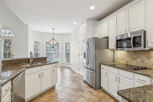 kitchen with white cabinets, appliances with stainless steel finishes, a chandelier, and dark stone counters