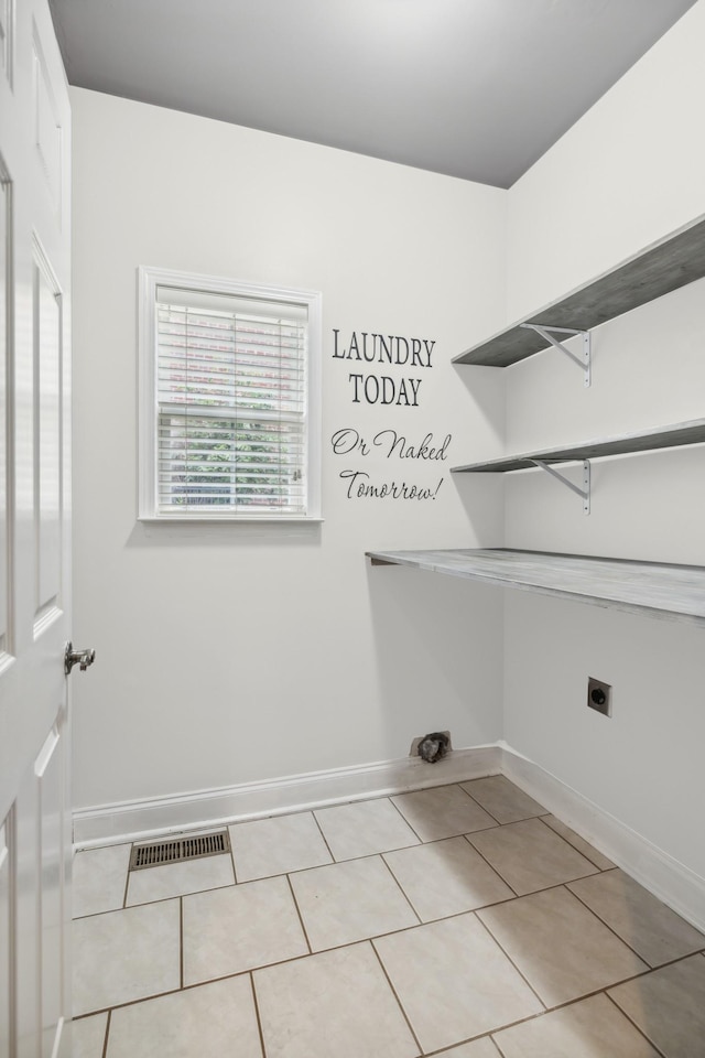 laundry area with hookup for an electric dryer and light tile patterned floors