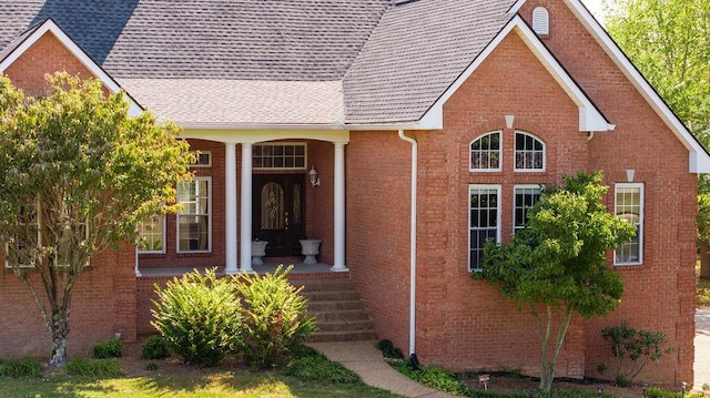 exterior space featuring brick siding and a shingled roof