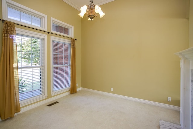 carpeted spare room with ornamental molding and a chandelier