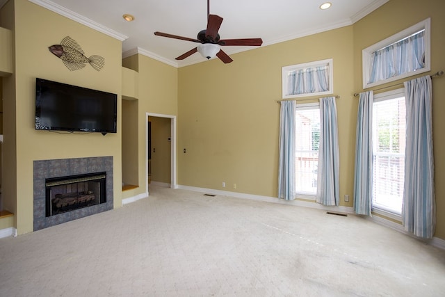 unfurnished living room with carpet flooring, ceiling fan, a tile fireplace, and ornamental molding