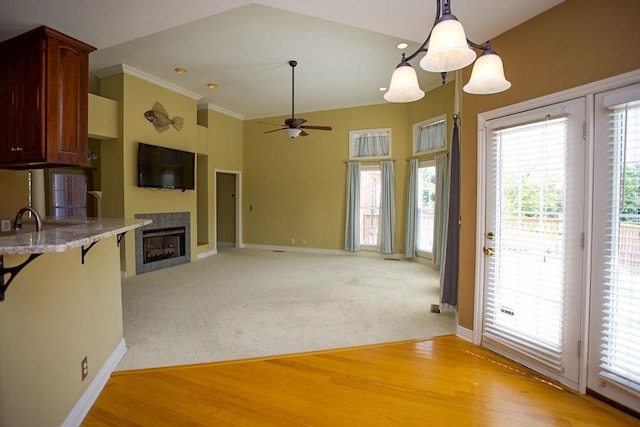 kitchen featuring light colored carpet, light wood-style flooring, baseboards, and a ceiling fan