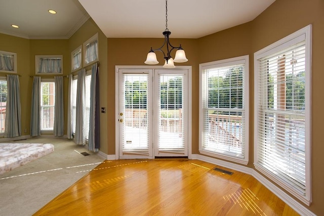 doorway to outside with visible vents, crown molding, recessed lighting, and a chandelier