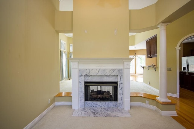 unfurnished living room with ornate columns, a high ceiling, a fireplace, and baseboards