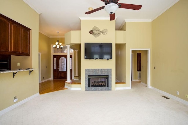 living area featuring light carpet, ceiling fan with notable chandelier, visible vents, and crown molding