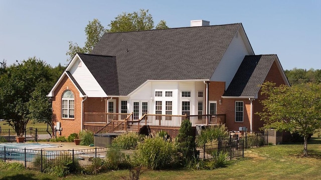 back of house with fence, a deck, a fenced in pool, brick siding, and a yard