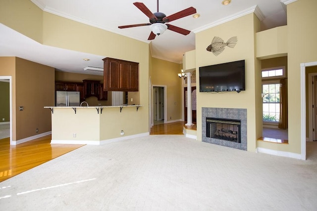 living area with a fireplace, high vaulted ceiling, ceiling fan, and crown molding