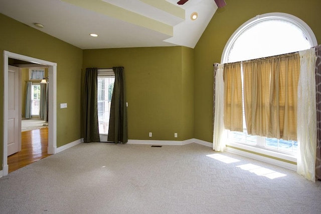 empty room featuring carpet flooring, a ceiling fan, lofted ceiling, baseboards, and visible vents