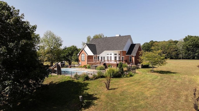 back of house with fence, a deck, brick siding, and a yard