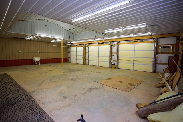 garage with a sink, a wall unit AC, and metal wall