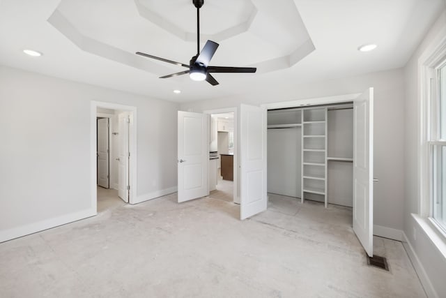 unfurnished bedroom featuring a raised ceiling, ceiling fan, and a closet