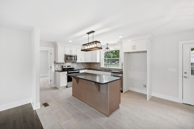 kitchen with hanging light fixtures, a center island, appliances with stainless steel finishes, and white cabinetry