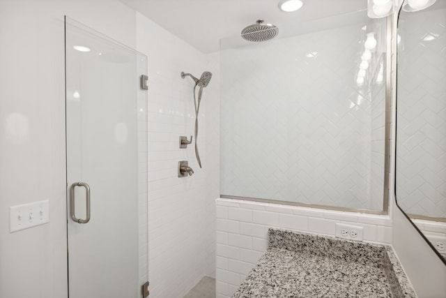 bathroom featuring tile walls, walk in shower, and vanity