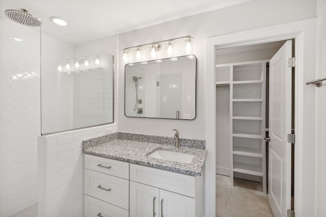 bathroom featuring tiled shower and vanity