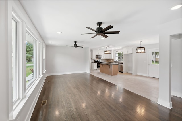 unfurnished living room with hardwood / wood-style floors, ceiling fan, and a wealth of natural light