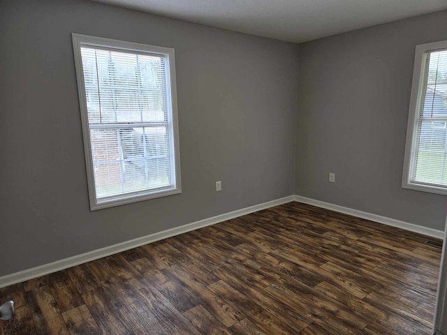 spare room featuring a wealth of natural light and dark hardwood / wood-style floors