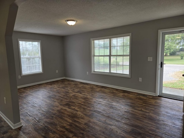 unfurnished room with a textured ceiling and dark hardwood / wood-style floors