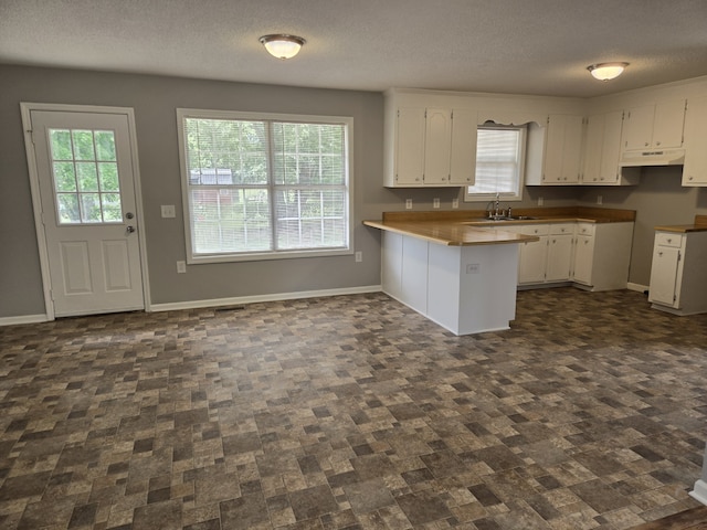 kitchen featuring white cabinetry, sink, kitchen peninsula, and a textured ceiling