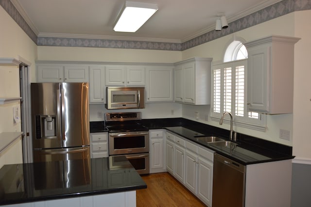 kitchen featuring appliances with stainless steel finishes, crown molding, white cabinetry, and sink