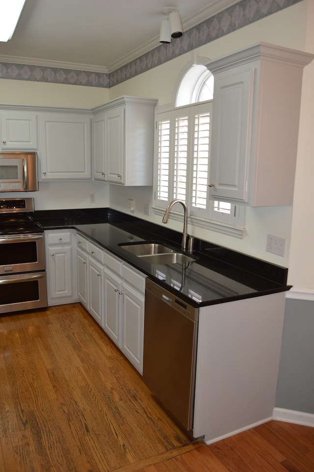 kitchen featuring ornamental molding, white cabinetry, dark hardwood / wood-style flooring, sink, and appliances with stainless steel finishes