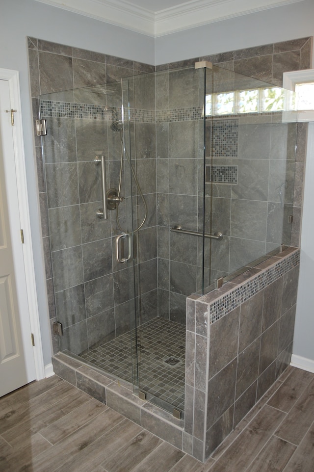 bathroom with a shower with shower door, ornamental molding, and hardwood / wood-style flooring