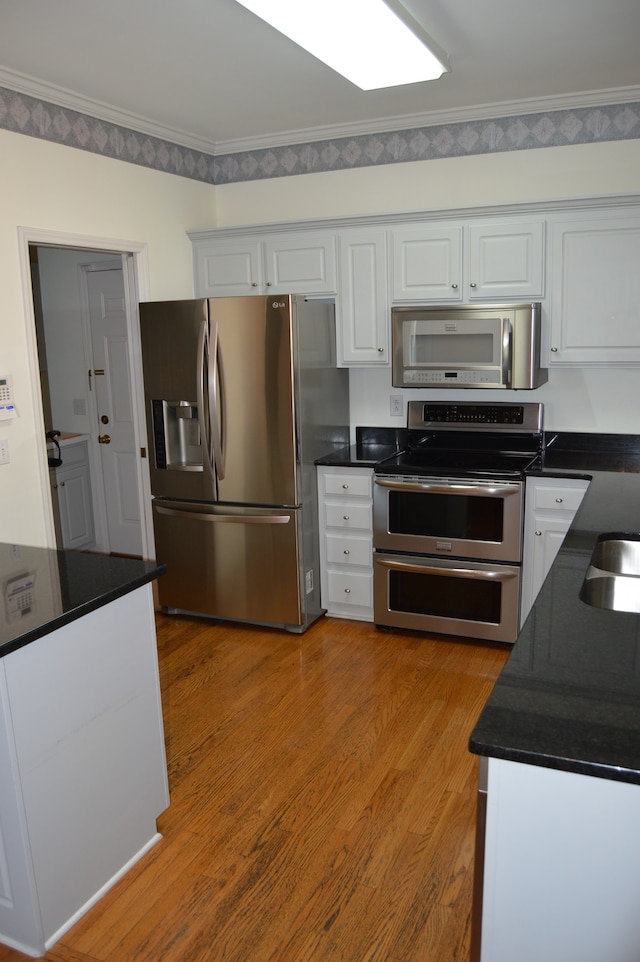 kitchen with white cabinets, appliances with stainless steel finishes, crown molding, and light hardwood / wood-style flooring