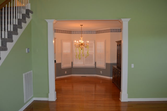 unfurnished dining area featuring crown molding, an inviting chandelier, and hardwood / wood-style flooring