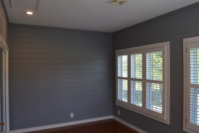 spare room with ornamental molding and wood walls