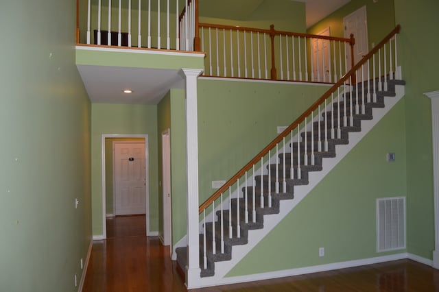 stairs featuring a towering ceiling and hardwood / wood-style flooring