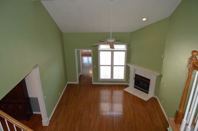 unfurnished living room featuring ceiling fan, a tiled fireplace, and light wood-type flooring