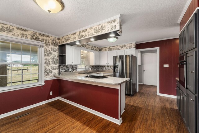 kitchen with white cabinets, kitchen peninsula, stainless steel appliances, a textured ceiling, and dark hardwood / wood-style floors