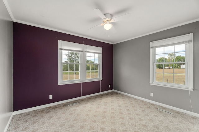 empty room with crown molding, ceiling fan, light colored carpet, and plenty of natural light