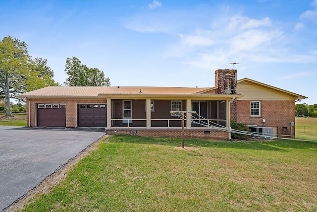 view of front of home featuring a front yard, driveway, an attached garage, a sunroom, and brick siding