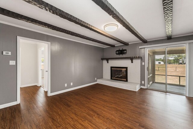 unfurnished living room featuring beamed ceiling, dark wood-type flooring, and a brick fireplace