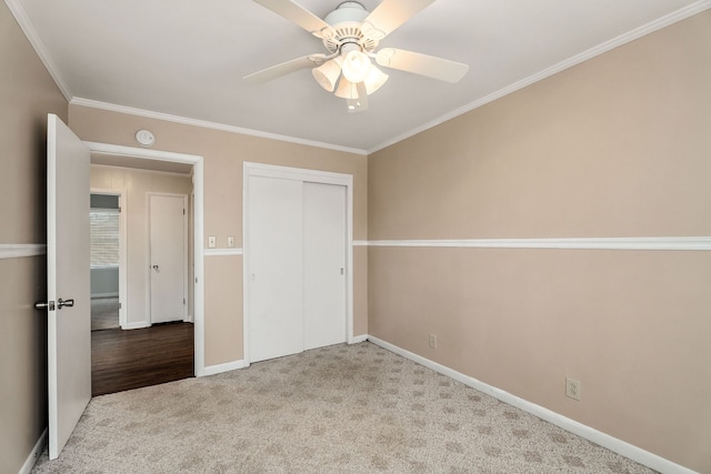 unfurnished bedroom featuring crown molding, ceiling fan, light colored carpet, and a closet