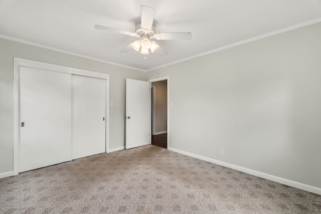 unfurnished bedroom with a closet, ceiling fan, carpet flooring, and crown molding