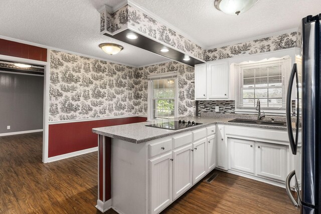 kitchen featuring white cabinetry, kitchen peninsula, dark hardwood / wood-style floors, and stainless steel refrigerator