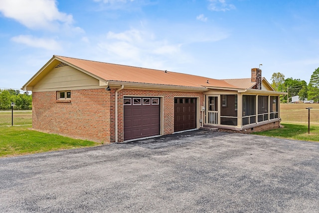 single story home featuring a garage, a sunroom, and a front yard