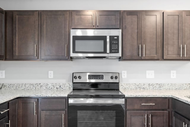 kitchen with dark brown cabinets, stainless steel appliances, and light stone countertops